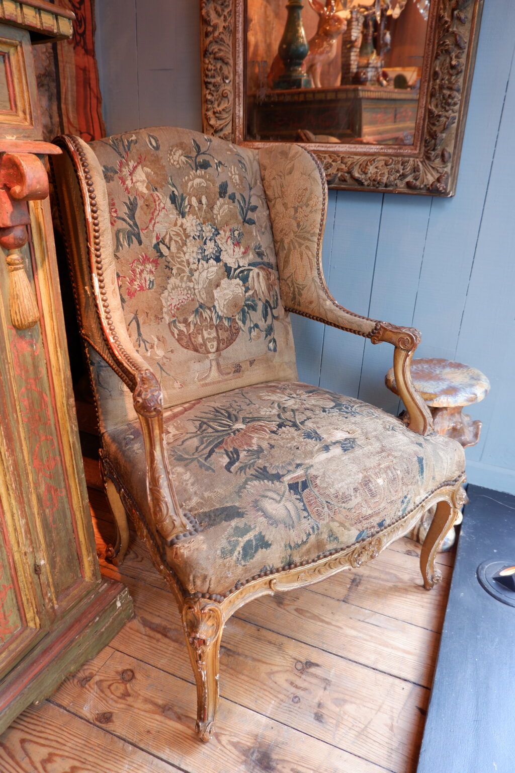 Fauteuil Régence à oreilles en bois doré recouvert d’une fine tapisserie d’époque XIXe