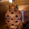Suspension en tôle dorée et ajourée, ornée de cabochons en verre polychrome facetés -France début XXème