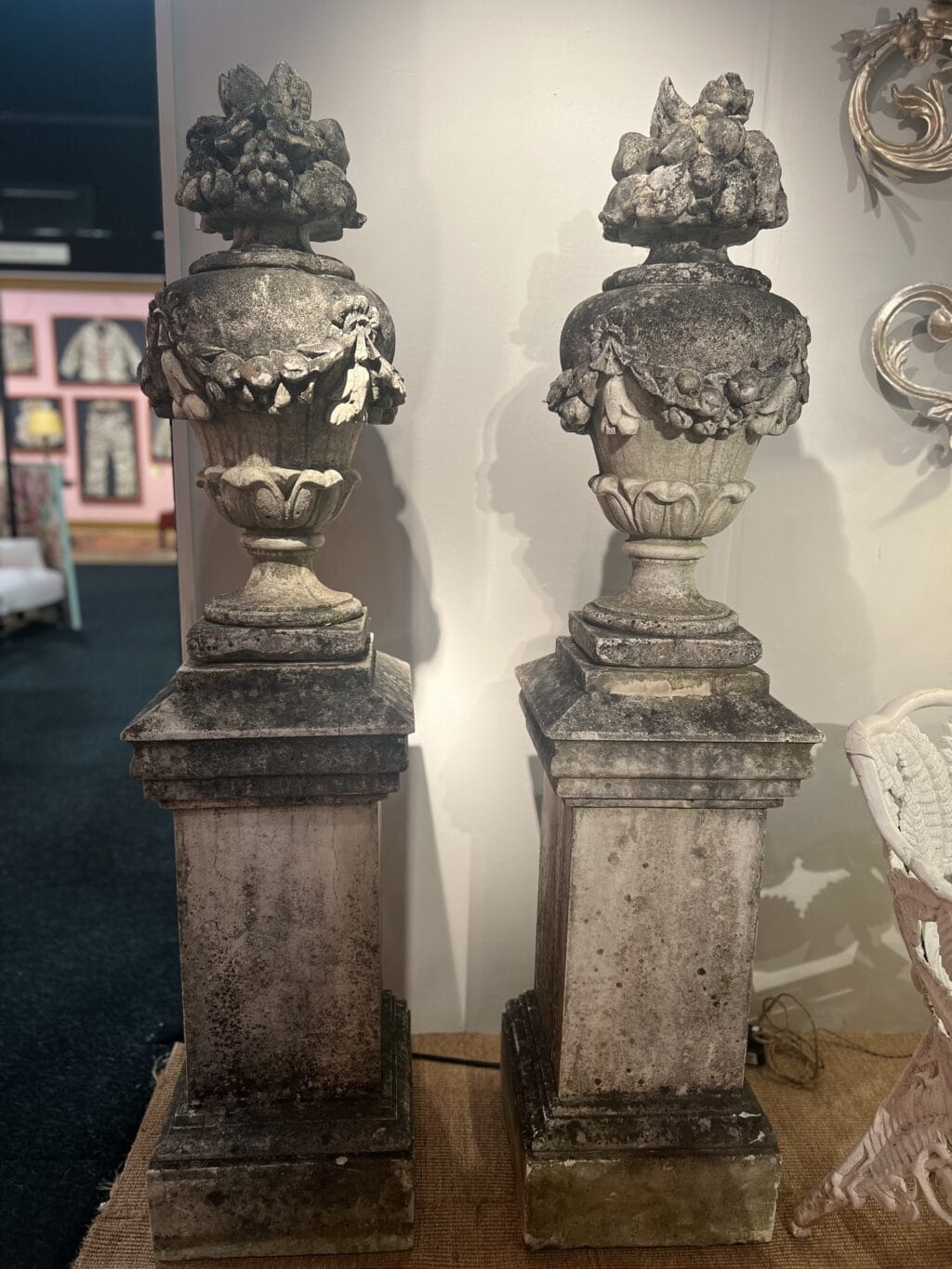 Paire de vases en pierre reconstituée ornés de guirlandes de fleurs et de fruits sur le dessus.