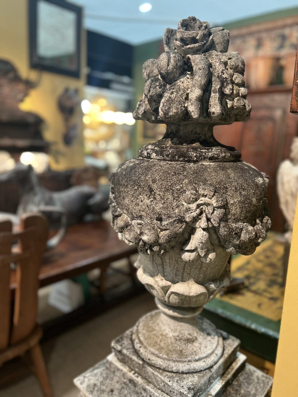 Paire de vases en pierre reconstituée ornés de guirlandes de fleurs et de fruits sur le dessus.