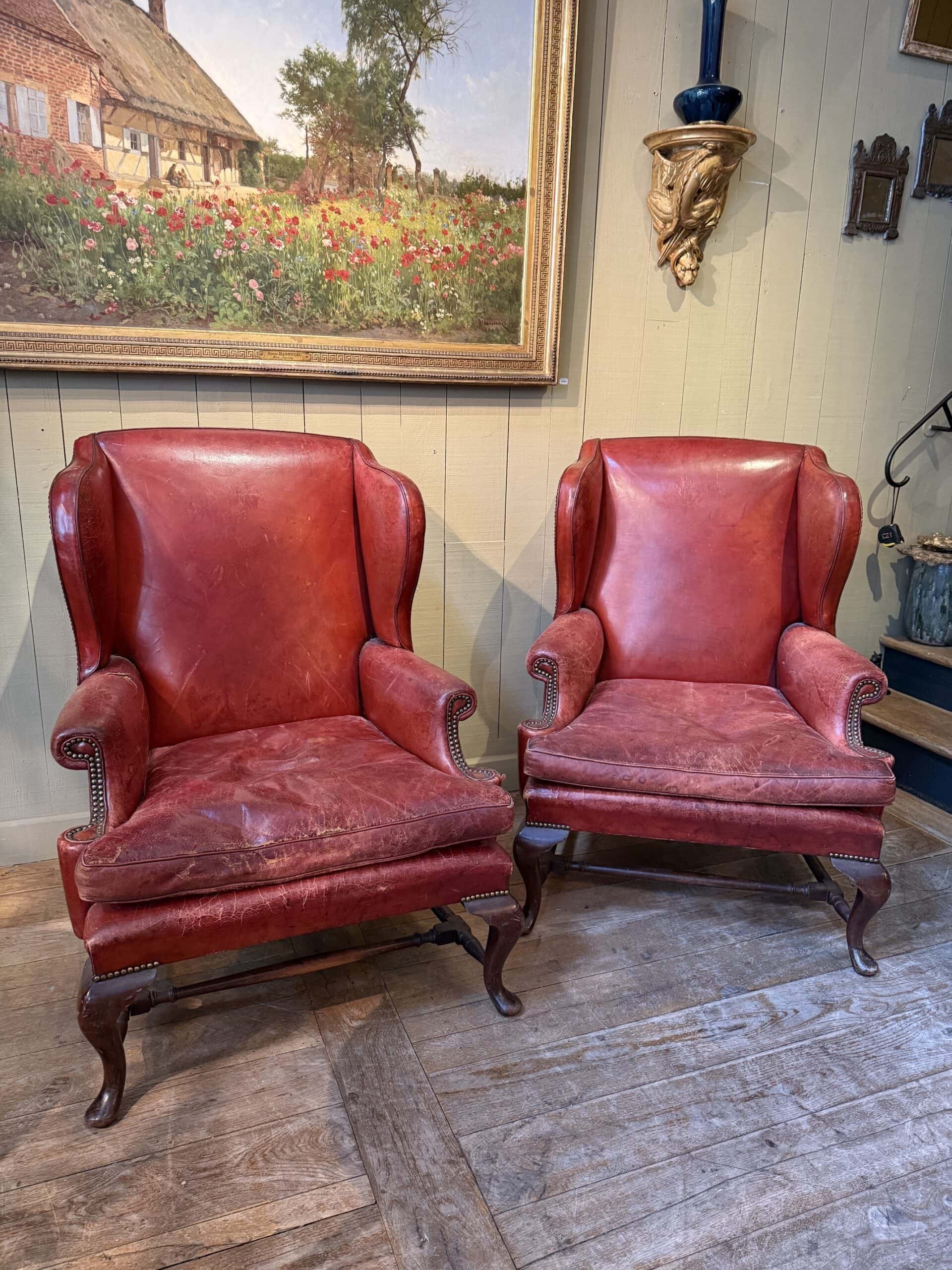 Paire de grands fauteuils à oreilles en cuir rouge